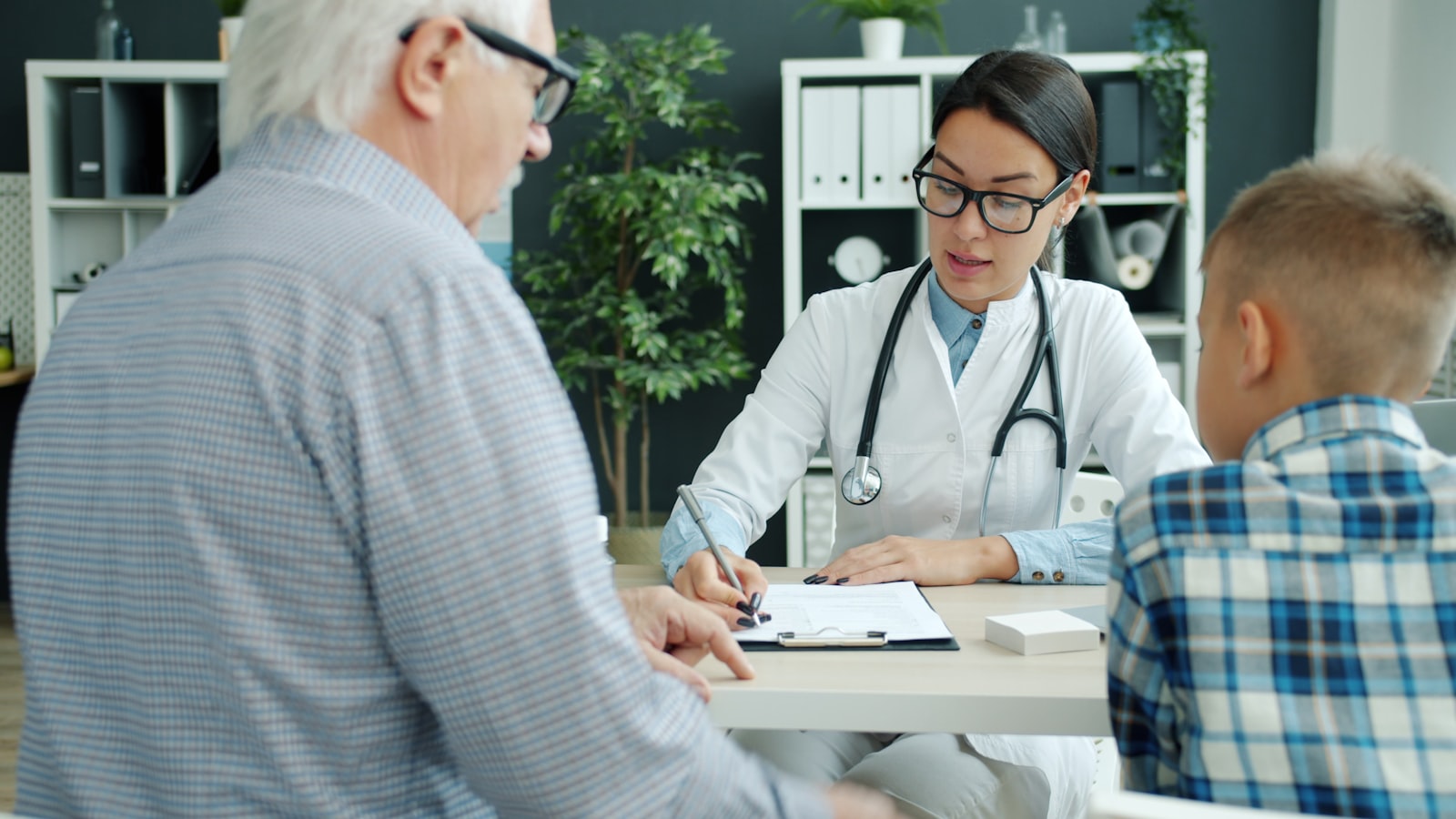 Healthcare worker speaking with an elderly patient and their family: aging is one of the core structural drivers of Hong Kong's medical inflation.